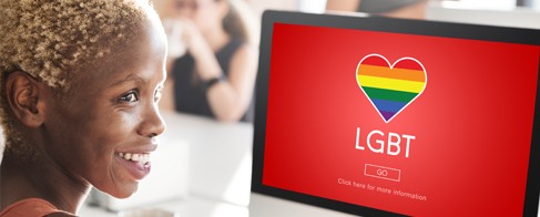  A woman smiles as she looks at a computer with a LGBTQ logo
